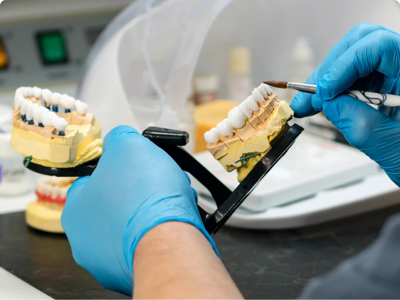 Gloved hands working on dental prosthetics