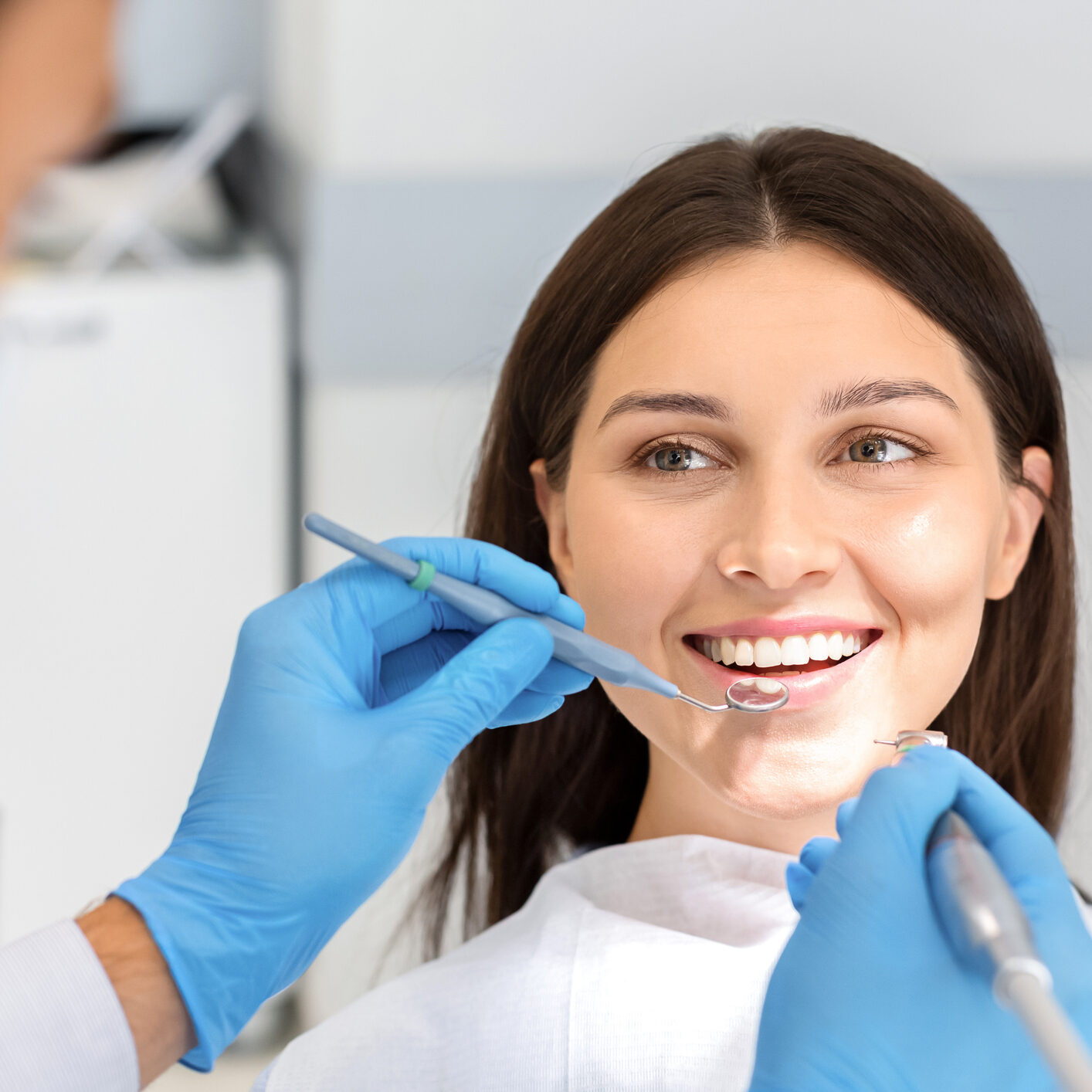 Smiling pretty woman looking with trust at dentist doctor during treatment